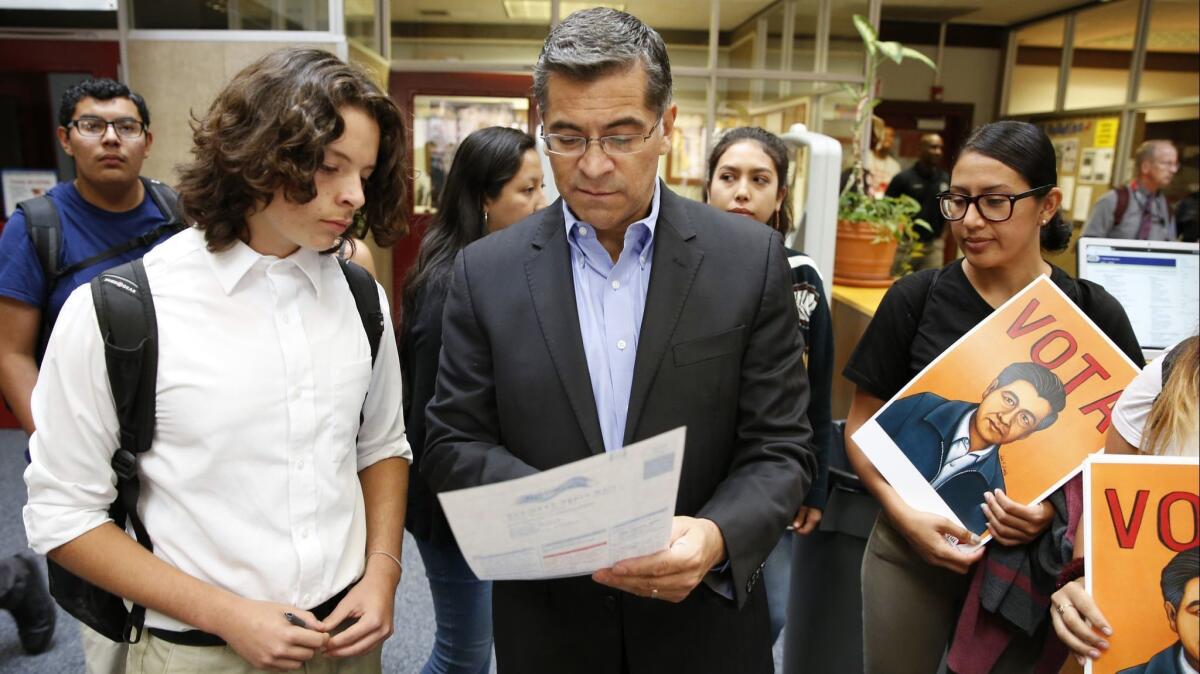 Atty. Gen. Xavier Becerra helps a student fill out a voter registration form in Sacramento in September.