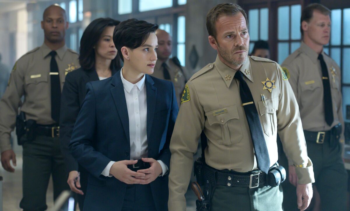 A woman and a man in a sheriff's uniform walk together.