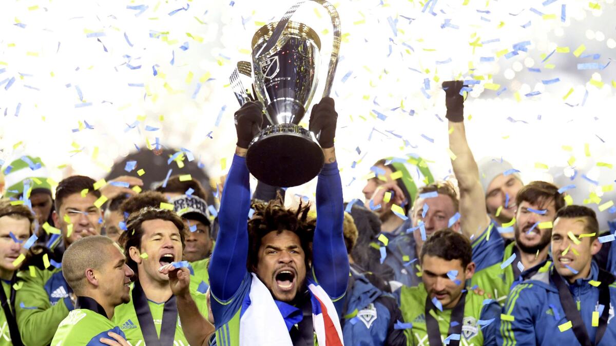 Seattle's Roman Torres hoists the trophy after the Sounders defeated Toront for the MLS Cup title on Saturday.