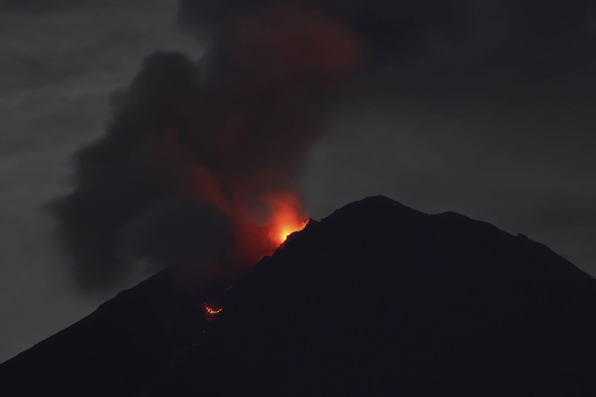 The crater of Mount Semeru glows from hot lava in Lumajang, East Java, Indonesia, early Wednesday, Dec. 8, 2021. The 3,676-meter (12,060-foot) volcano erupted on Saturday killing a number of people and left thousands others homeless. (AP Photo/Trisnadi)