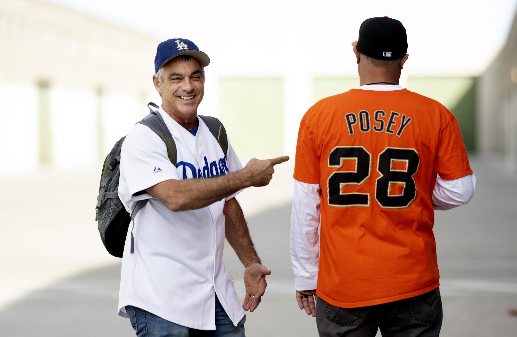 Dodgers fan Chris Rinaldi smiles and points to his friend, who is wearing a Buster Posey jersey