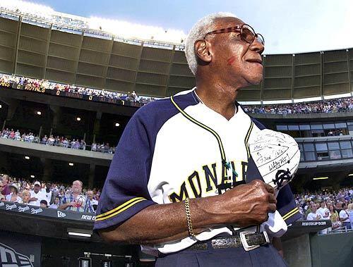 With lipstick on his cheek from greeting fans, Buck O'Neil stands for the National Anthem at Kaufmann Stadium in Kansas City, Mo.