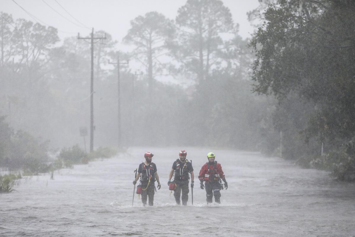Rescue workers with Tidewater Disaster Response wade through a tidal surge on a highway.