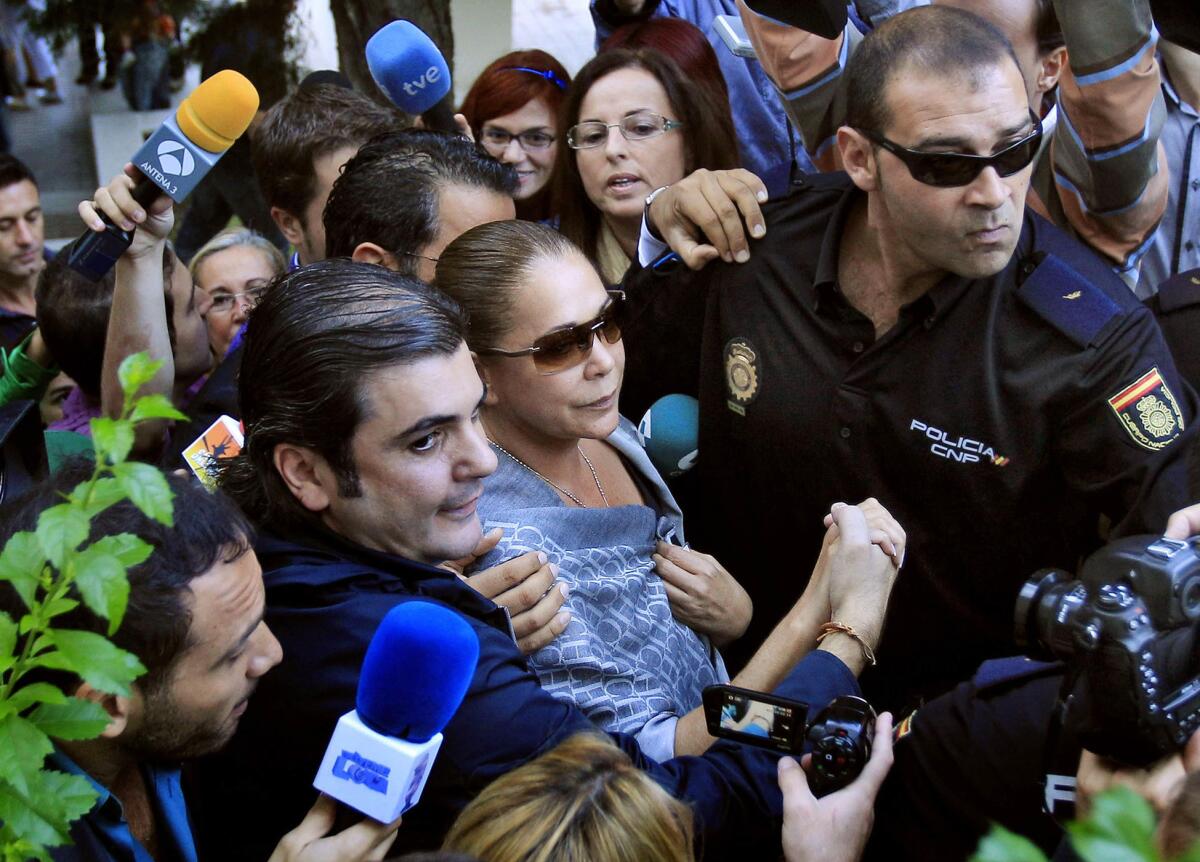 FILE - In this Oct. 14, 2010 file photo, a police officer escorts Spanish singer Isabel Pantoja, center, as she arrives at the court in Marbella, southern Spain. Pantoja is getting out of prison for four days after completing part of her two-year sentence for money laundering. The 58-year-old Pantoja smiled and waved to fans and journalists, Monday June 1, 2015 as she left the Alcala de Guadiara jail in Seville province. The fixture in Spain's gossip magazines and TV shows qualified for the pass to visit relatives but must return to jail later this week. (AP Photo/Sergio Torres, File)