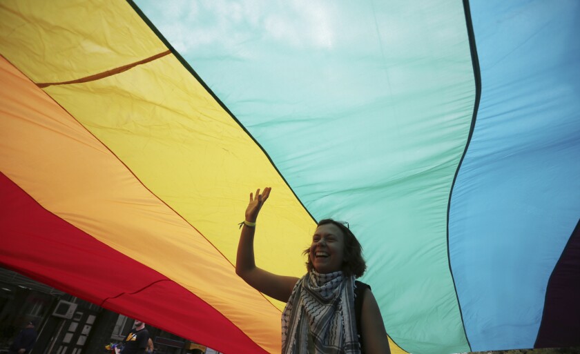FILE - A woman stands under the rainbow flag during gay pride rally in the Bulgarian capital of Sofia, Sept. 21, 2013. A ruling by the European Union's top court on Tuesday, Dec. 14, 2021 has given a boost to the rights of same-sex parents and their children in the 27-nation bloc. The European Court of Justice said that a child with two mothers certified in one EU nation must also be recognised by the other EU member states as such. (AP Photo/Valentina Petrova, File)