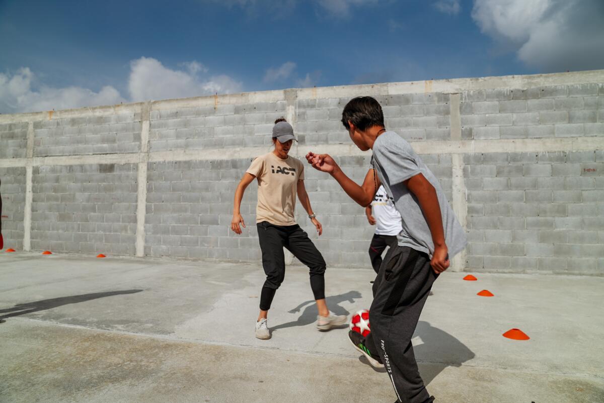 Sara-Christine Dallain tests her soccer skills against a pair of children at the Sends de Vida migrant shelter.
