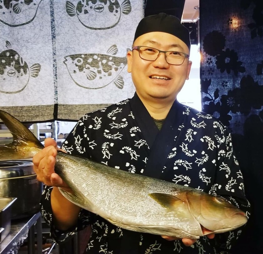 Haru Sushi manager and chef Nak Joon Kim holds a kanpachi fish.