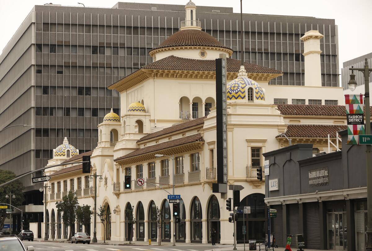 An ornate multistory building with a ground-floor row of large arched windows, tile roof and domes.