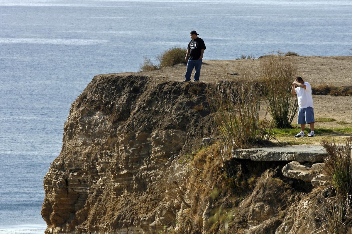 Eddie Raya, 25, and Sergio Diaz, 43, both of Harbor City, look out over the cliff of Point Fermin in San Pedro. On Monday night, police say a driver fleeing police drove off the edge and somehow survived.