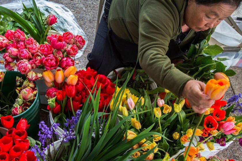 Mai Yang, of Salem, creates handmade bouquets of fresh flowers at the Sun Sweet flower Garden booth on opening day of the Tuesday Lane County Farmers Market in downtown Eugene, Ore., on Tuesday, May 2, 2017. (Brian Davies /The Register-Guard via AP)