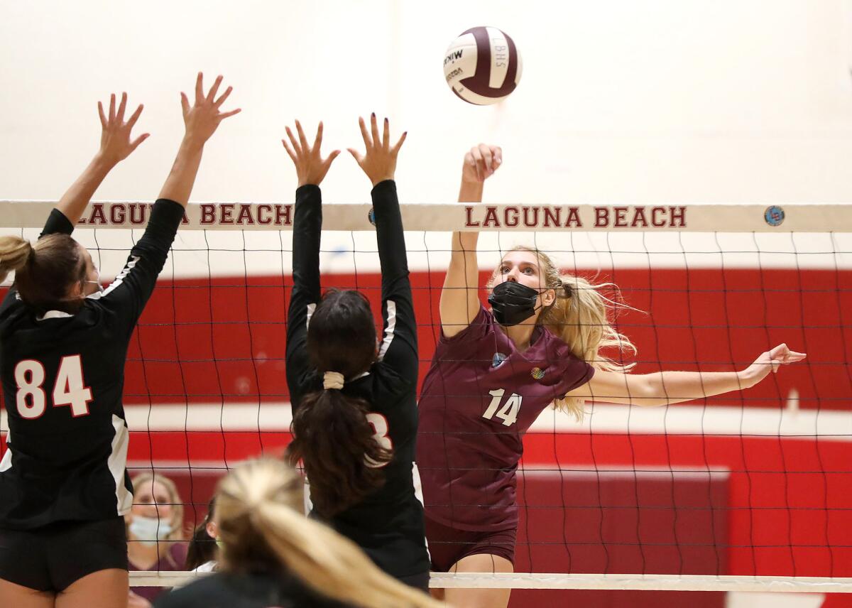 Laguna Beach's Sophie Reavis (14) pokes the ball on the run past two La Canada Flintridge blockers for a point on Oct. 21.