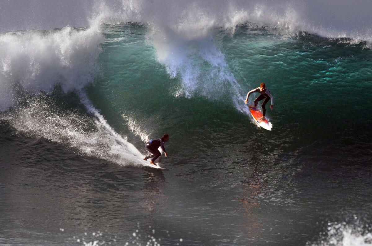 A pair of surfers slide down a huge wave at the Wedge off Newport Beach on Aug. 27 as thousands of spectators looked on.