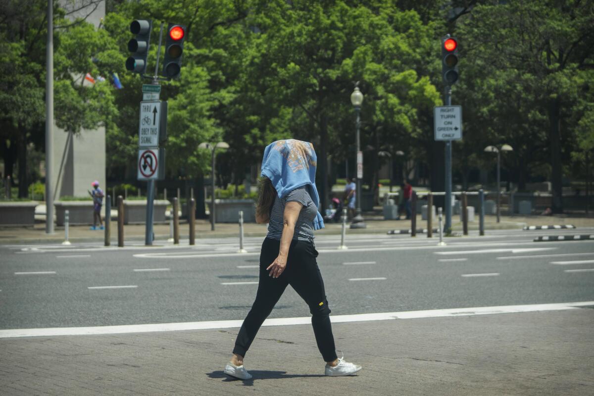 Una mujer camina con una sudadera en la cabeza para protegerse del sol en el centro de Washington