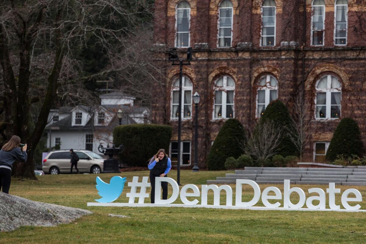 A student poses with a sign promoting Saturday's Democratic presidential debate on the campus of Saint Anselm College in Manchester, N.H., where candidates Hillary Clinton, Bernie Sanders and Martin O'Malley are squaring off.