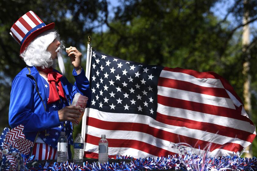 James Tyler, 19, tilts his head back so the popcorn he is eating on the back of a decorated Jeep won't catch on his artificial Uncle Sam mustache after Tuesday's Independence Day parade in Buffalo Gap, Texas Tuesday, July 4, 2023. (Ronald W. Erdrich /The Abilene Reporter-News via AP)