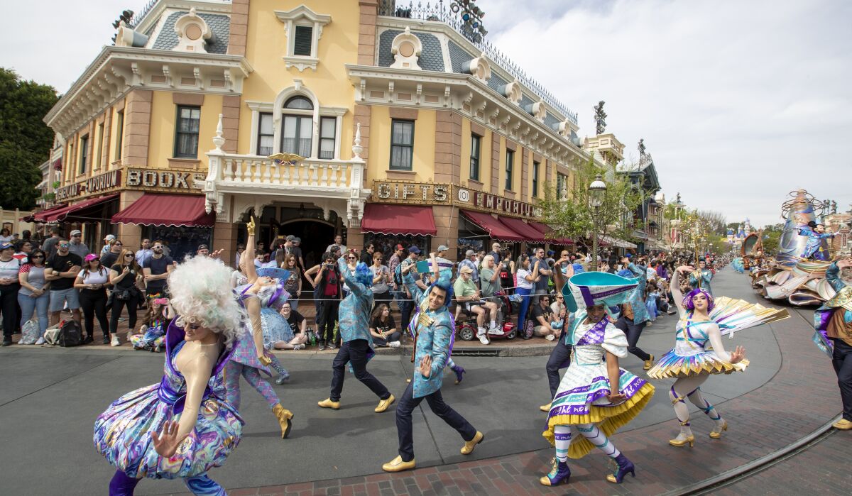 Dancers in vibrant costumes lead the Disneyland daytime parade called Magic Happens.