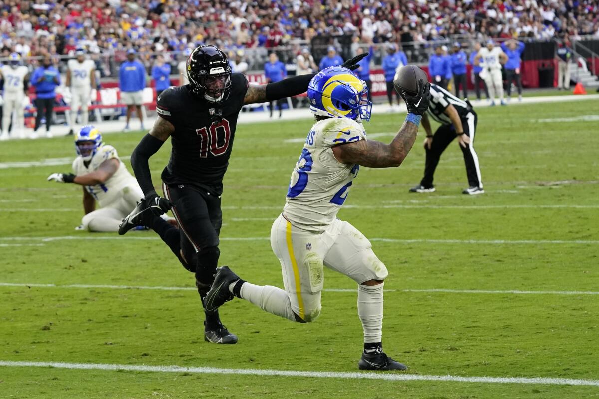 Rams geri koşuyor Kyren Williams, Cardinals'ın defans oyuncusu Josh Woods'un peşindeyken gol atmaya giden yolda pas atıyor.
