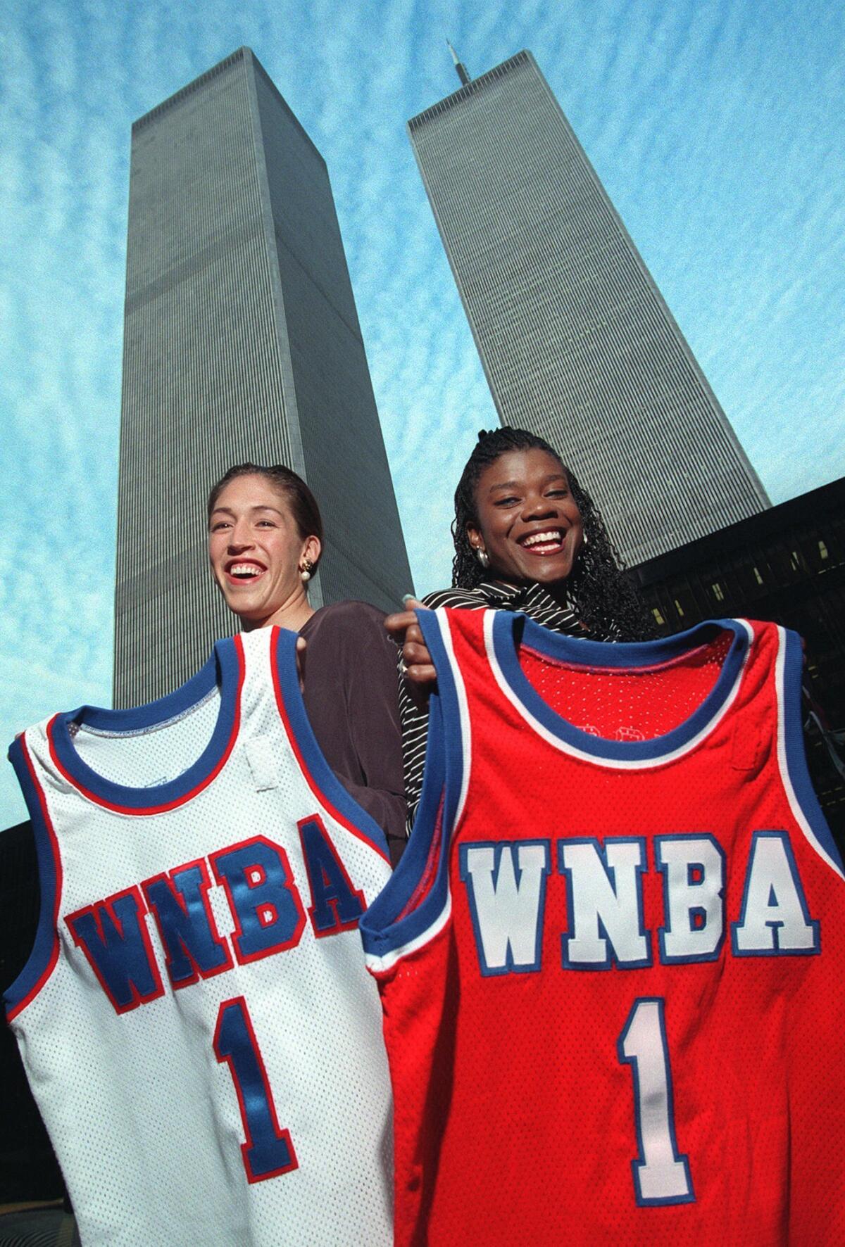Olympic gold medalists Rebecca Lobo, left, and Sheryl Swoopes display their jerseys for the inaugural season of the Women's National Basketball Assn. in the shadow of New York's World Trade Center on Oct. 23, 1996.