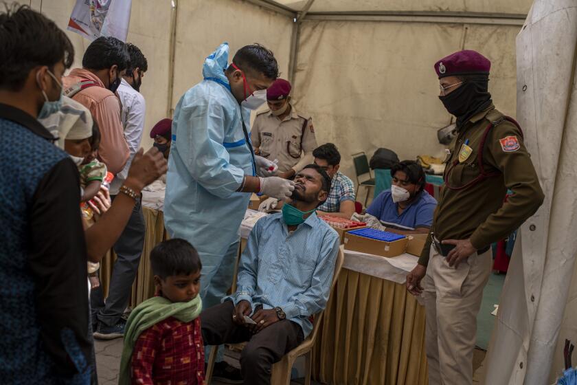 A health worker takes a nasal swab sample of a passenger to test for COVID-19 at a bus terminal in New Delhi, India, Wednesday, March 24, 2021. (AP Photo/Altaf Qadri)