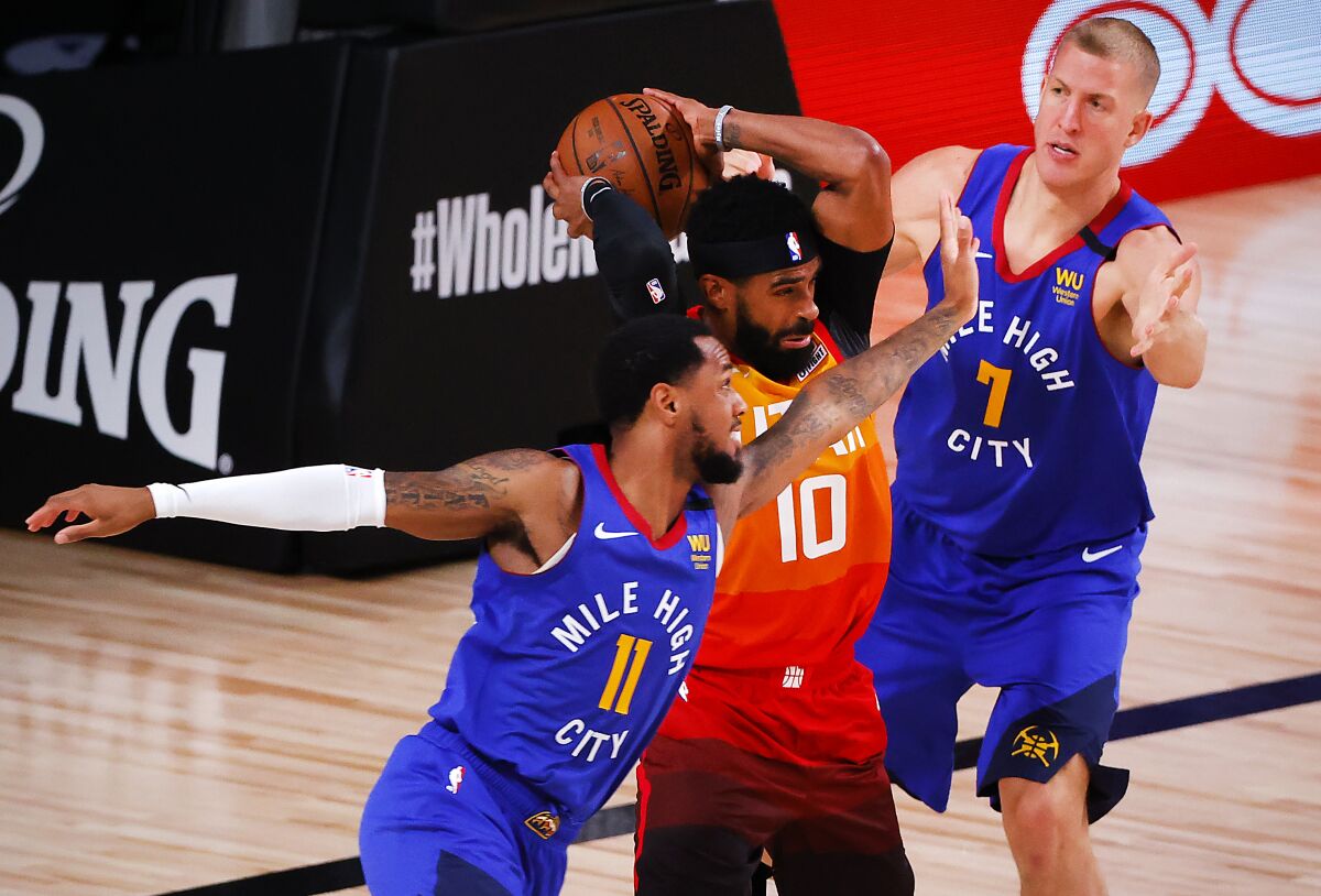 Utah Jazz's Mike Conley (10) rebounds against Denver Nuggets' Monte Morris (11) and Mason Plumlee (7) during the third quarter of an NBA basketball game Saturday, Aug. 8, 2020, in Lake Buena Vista, Fla. (Kevin C. Cox/Pool Photo via AP)