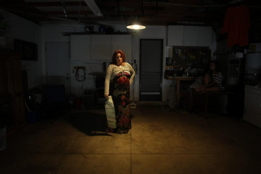 In her empty garage Lisa Twombly holds the contract for a used car she bought with a 21% dealer loan. The car soon needed repairs she felt the dealer should cover. When she quit making payments in protest, it was repossessed and set off a sequence of events that left Twombly and her 2 children homeless for 6 weeks.