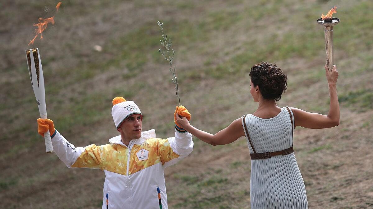 Actress Katerina Lehou, dressed as an ancient pagan priestess, passes an olive branch to torch bearer Apostolos Angelis, a Greek cross-country skier, during the lighting ceremony of the Olympic flame in southern Greece on Oct. 24.