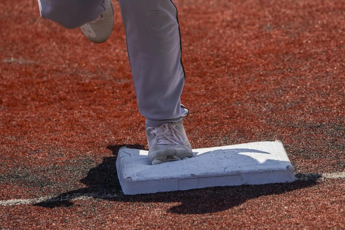 Larger bases are installed on the infield during a minor league baseball game.