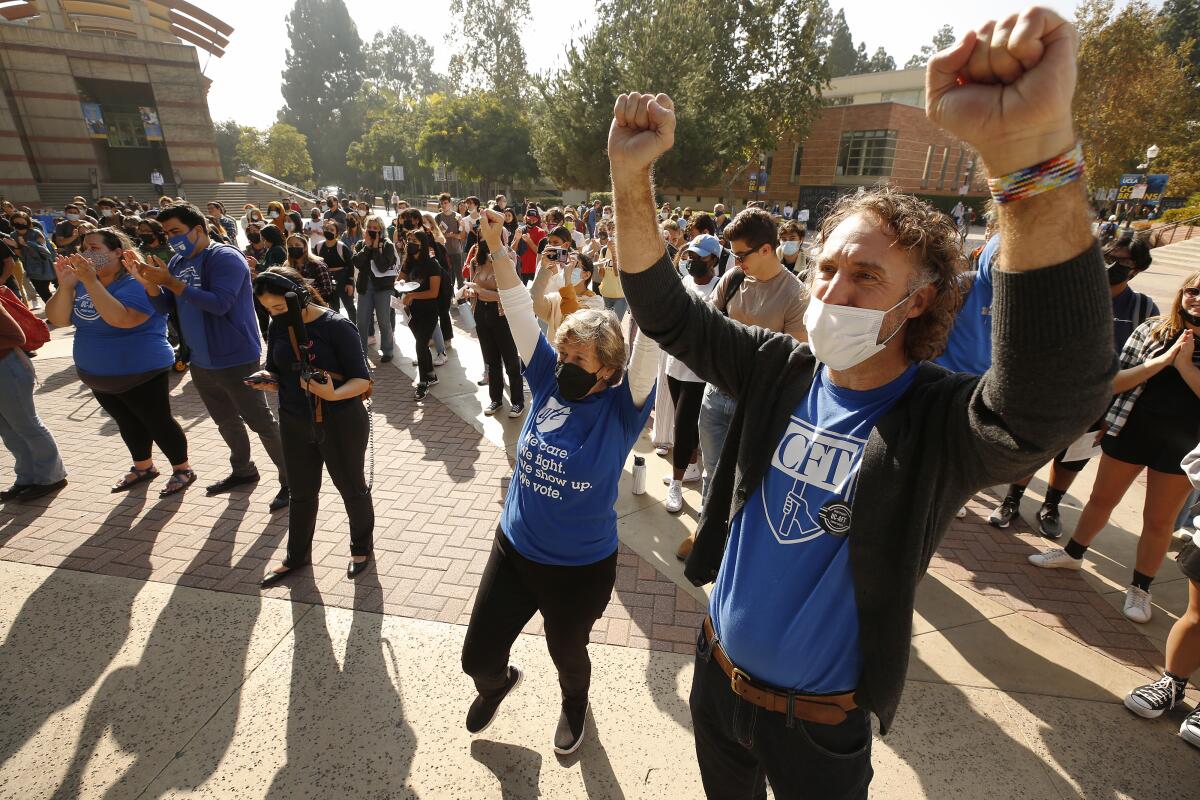 Two people amid a group raise their arms in triumph