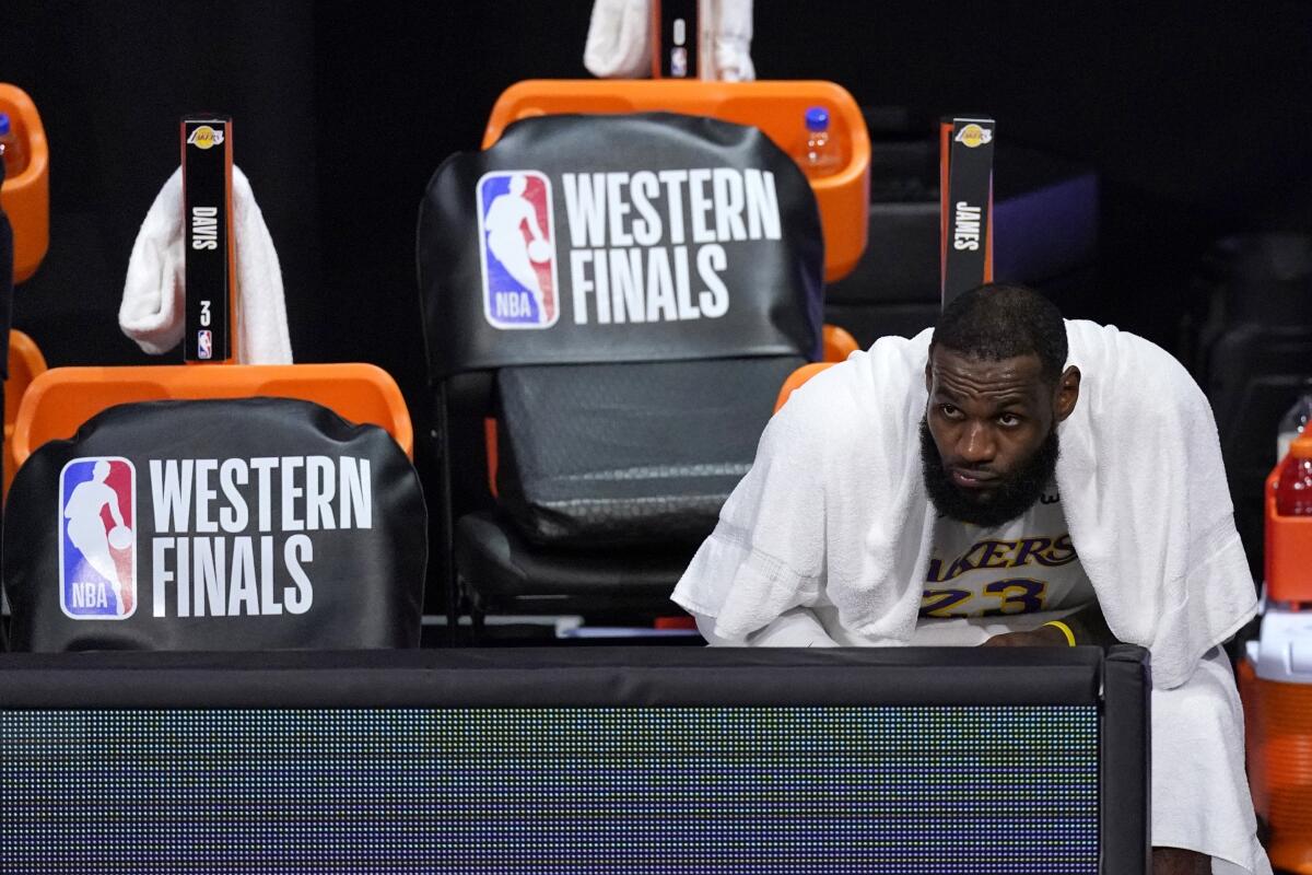 Lakers forward LeBron James watches play against the Denver Nuggets from the bench.