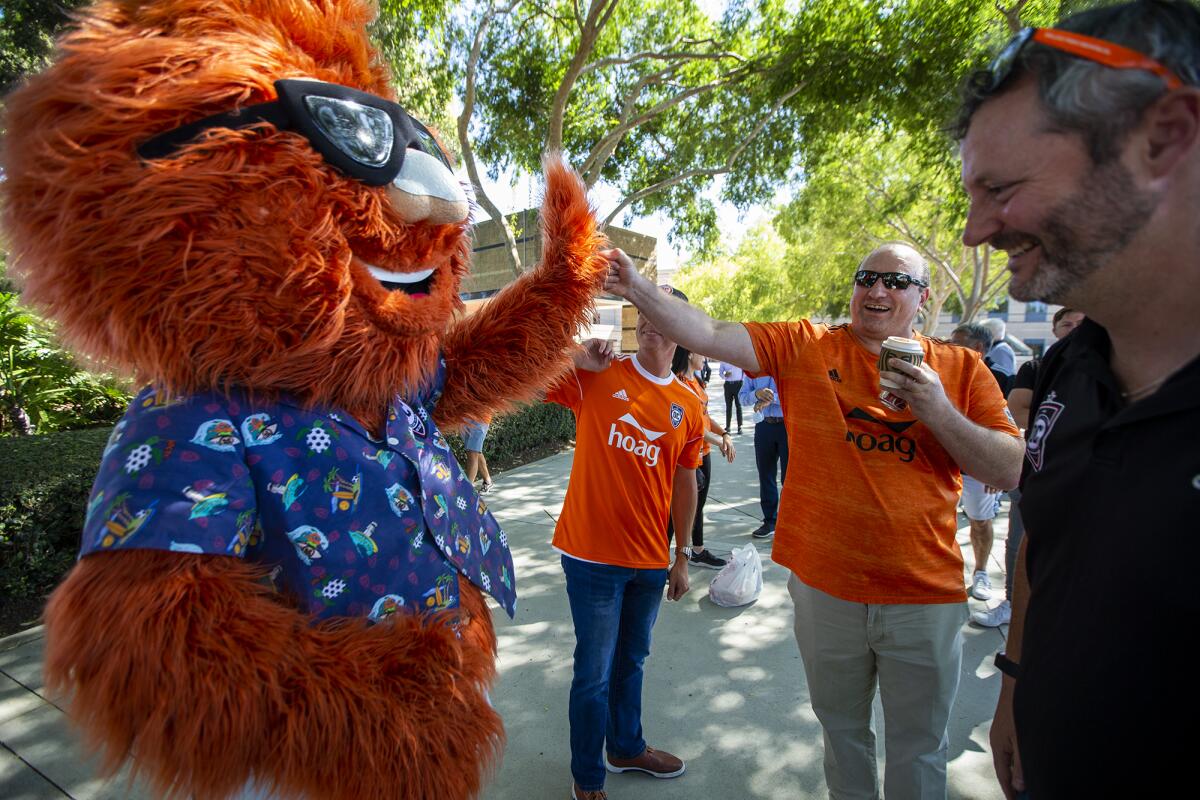 James Keston, the owner of the Orange County Soccer Club, high-fives the team mascot, Gnarly, outside Irvine City Hall.