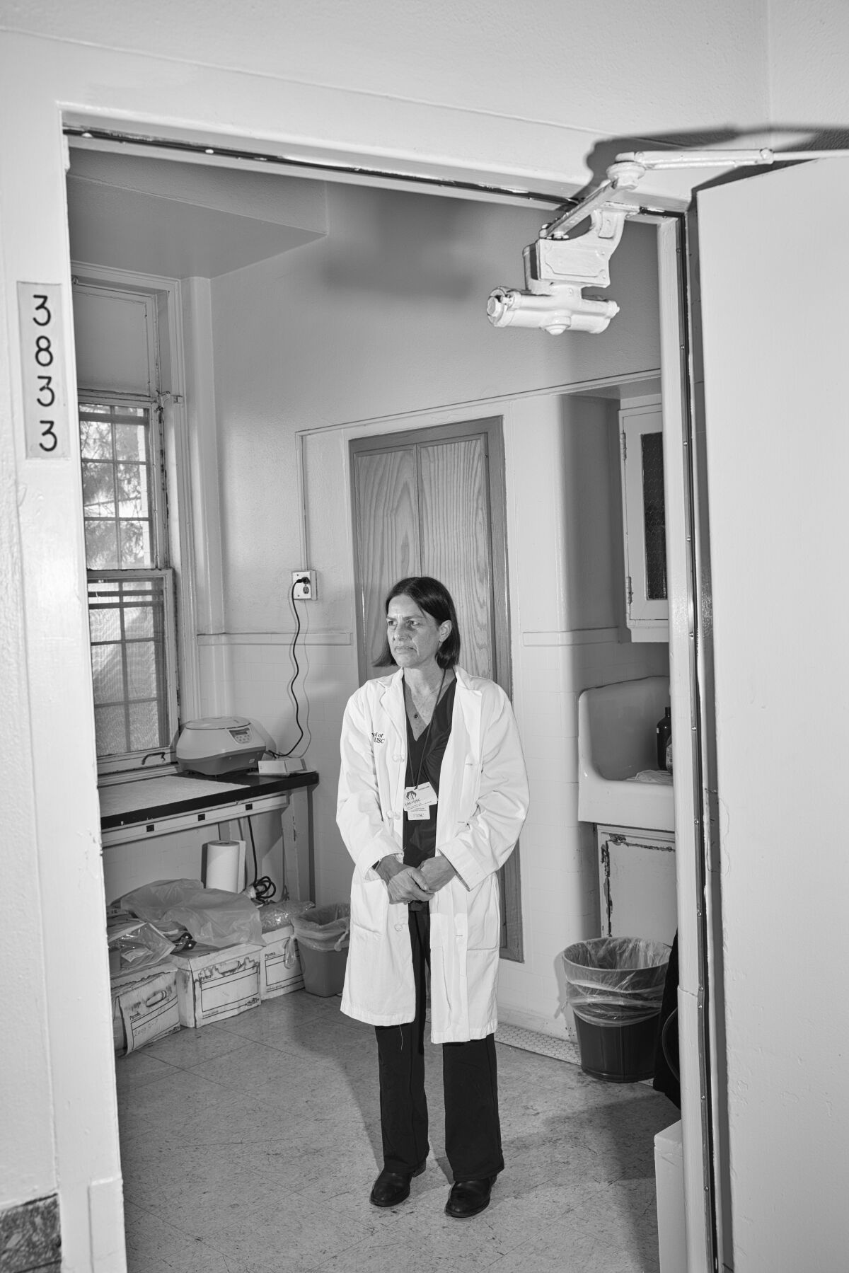 A researcher in a lab coat stands in her lab.