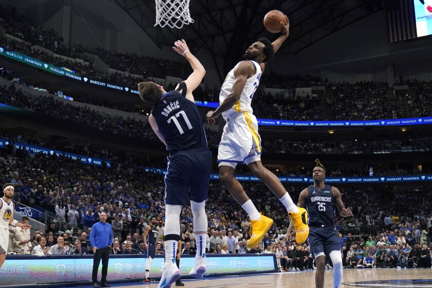 Golden State Warriors forward Andrew Wiggins dunks over Dallas Mavericks guard Luka Doncic.