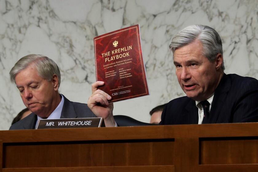 Senate Judiciary Committee member Sen. Sheldon Whitehouse (D-RI) holds a copy of "The Kremlin Playbook" while delivering remarks with Sen. Lindsey Graham at the conclusion of a hearing on Russian interference in the 2016 election, on May 8.