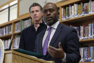 FILE — In this Oct. 31, 2019, file photo, state Superintendent of Public Instruction Tony Thurmond answers a reporter's question during a visit with Gov, Gavin Newsom, background, to Blue Oak Elementary School, in Cameron Park, Calif. Thurmond said on Wednesday, April 29, 2020, that California schools won't reopen until it can be done safely, due to the new coronavirus pandemic. (AP Photo/Rich Pedroncelli, File)