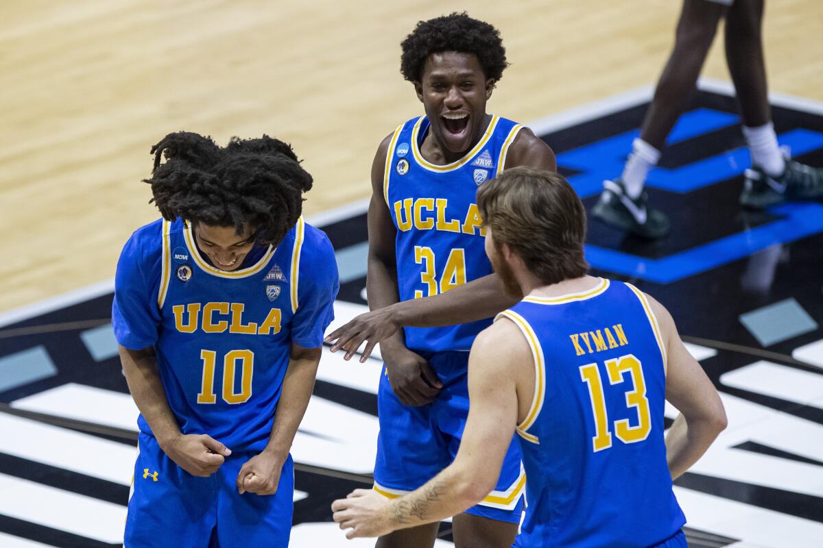 UCLA's Tyger Campbell (10), David Singleton (34) and Jake Kyman (13) celebrate following the team's 86-80 win.