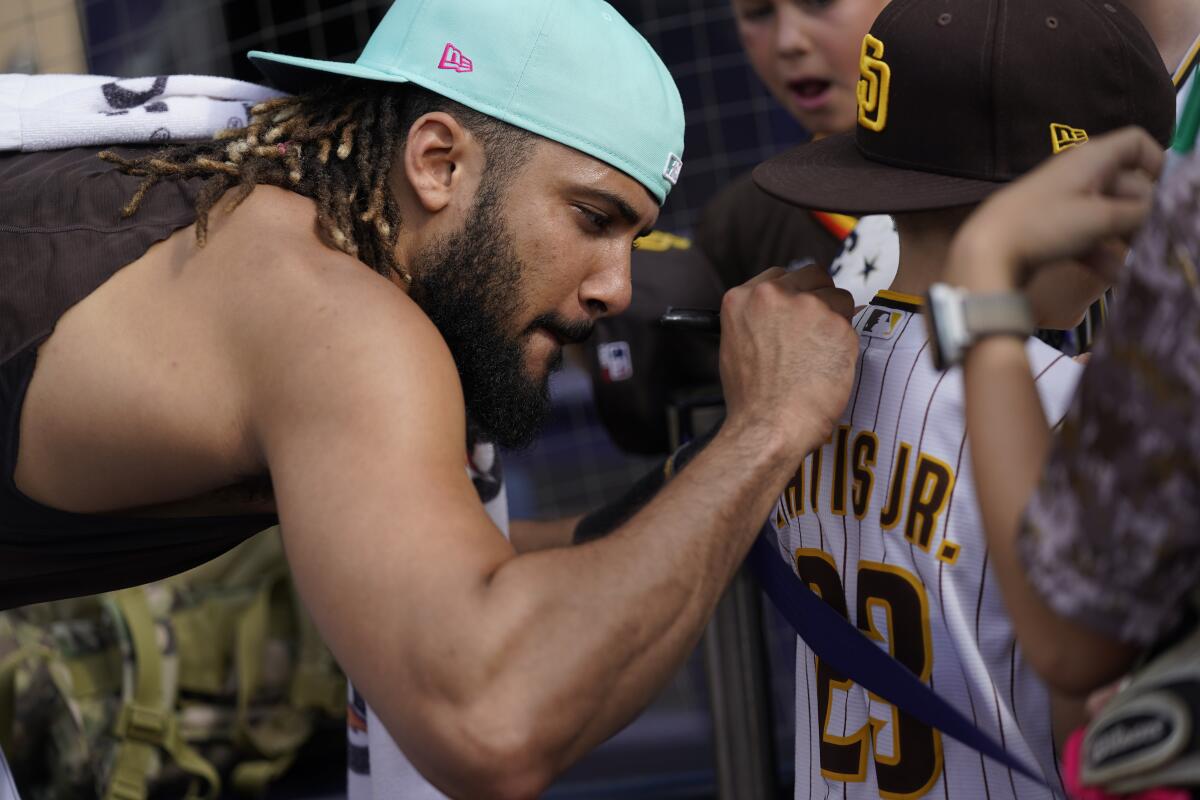 San Diego Padres' Fernando Tatis Jr signs autographs during batting practice before team's baseball game against the Colorado Rockies on Wednesday, Aug. 3, 2022, in San Diego. (AP Photo/Gregory Bull)