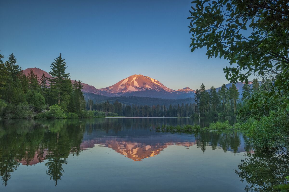 Mt. Lassen in the distance behind a lake and forest.