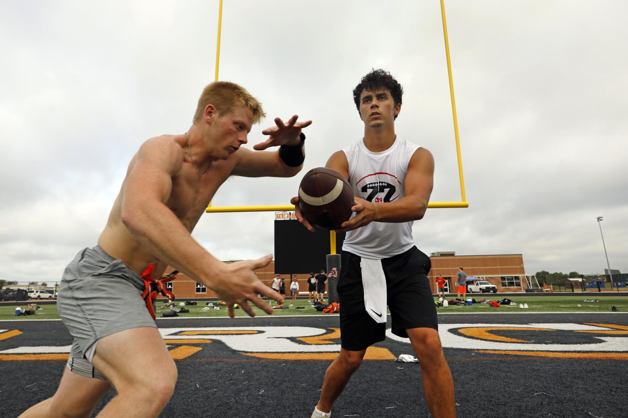 Ethan McBrayer, 17, right, hands off to Conner Smith, 16, left, during practice at Aledo High School.