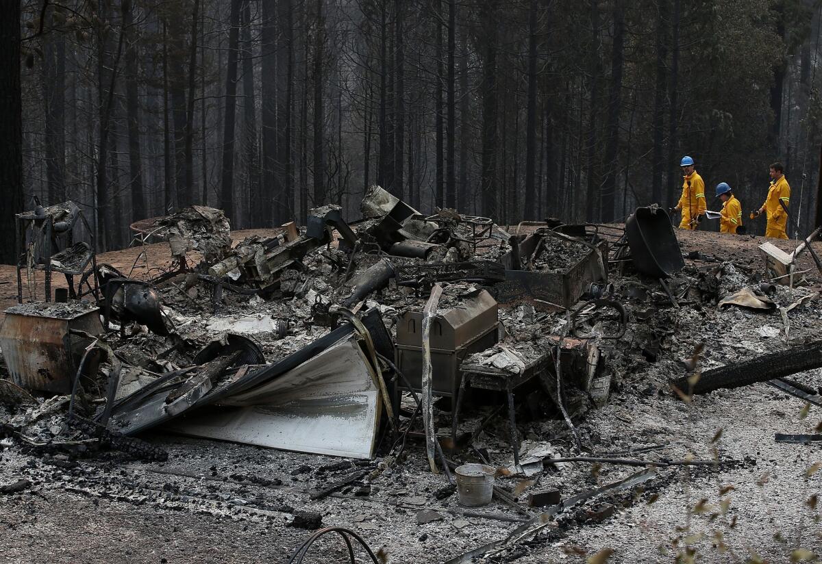 Officials inspect a structure that was destroyed by the King fire on Friday, Sept. 19, near Pollock Pines in northern California.