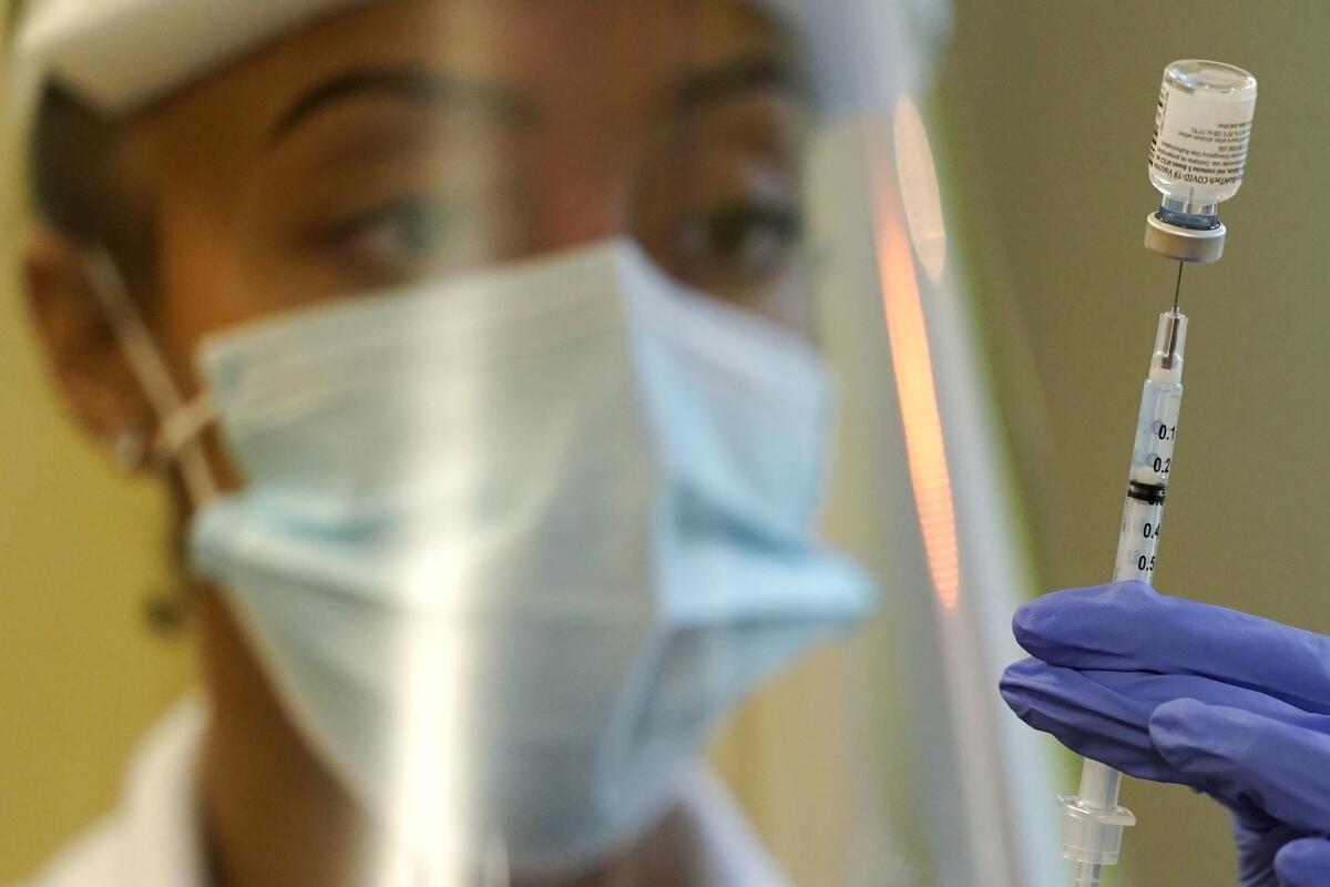 A pharmacist prepares a syringe of the Pfizer vaccine for COVID-19.