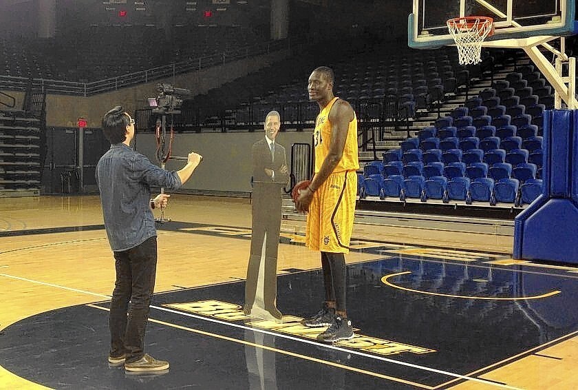 Wilbert Cheng, a student video producer/director, and Mamadou Ndiaye, UC Irvine's 7-foot-6 center, use a cardboard cutout of Obama as a prop for a video in which Ndiaye says: “Mr. President, we should play ball together.”