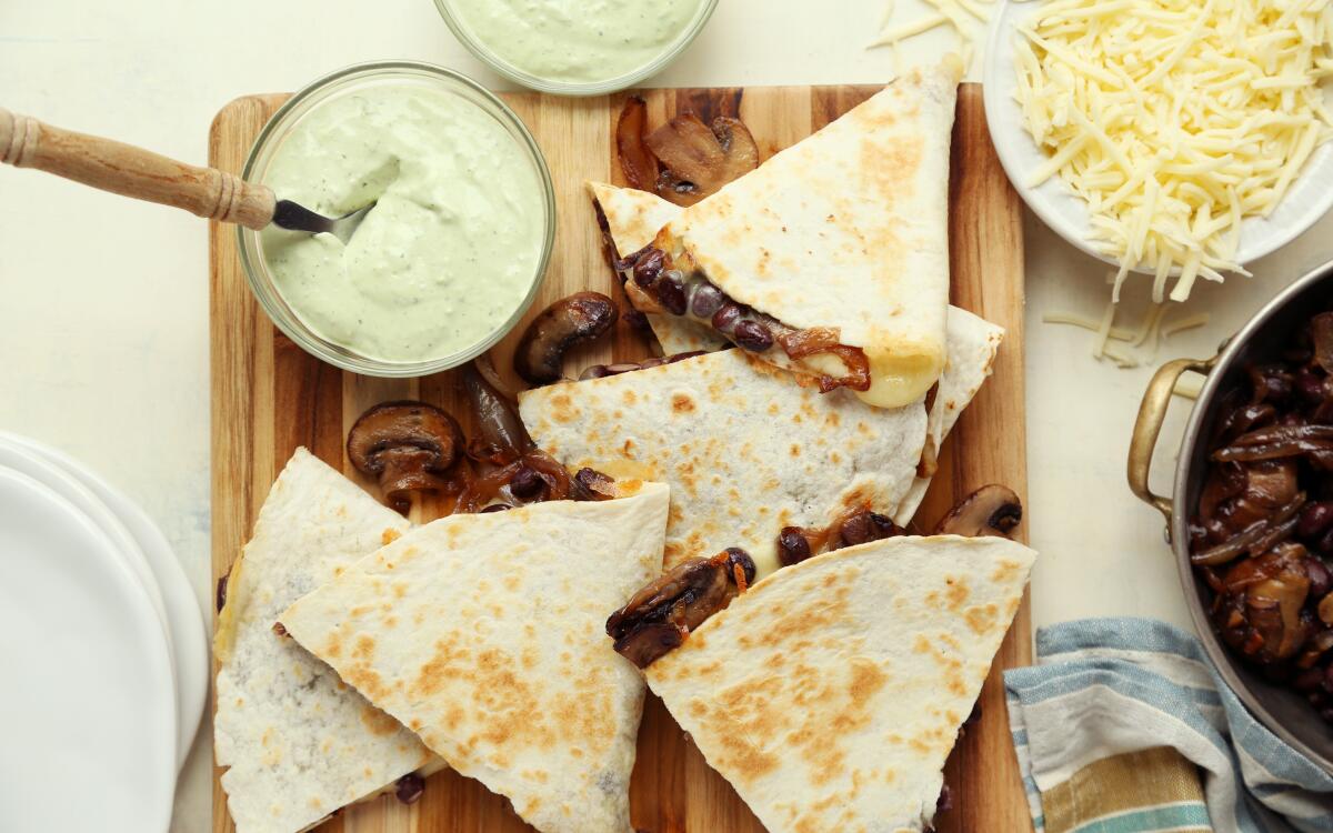 A bright avocado cream adds freshness to these cheesy vegetarian quesadillas teeming with mushrooms and black beans.