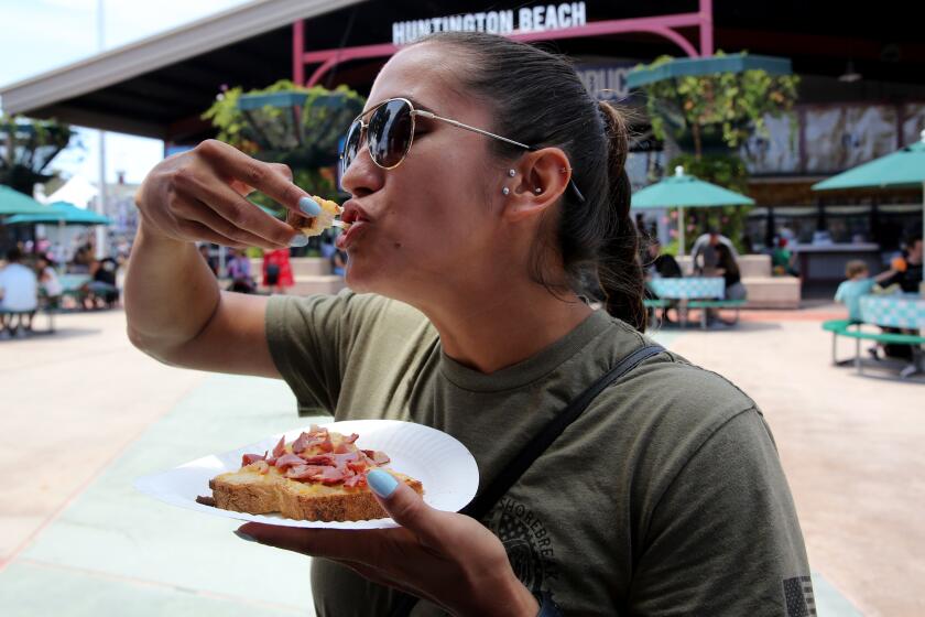 Rochelle Rivera, 30 of Huntington Beach, takes a bite of her pastrami on sourdough with cheese from Ten Pound Bun at the Orange County Fair in Costa Mesa on Thursday, July 21, 2022.