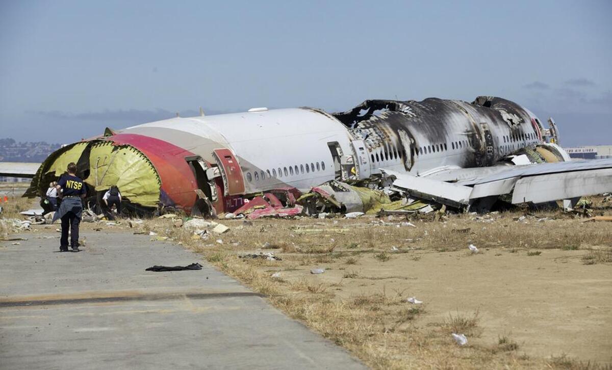 An National Transportation Safety Board investigator looks at the fuselage of the crashed Asiana Flight 214 during the first site assessment in San Francisco.