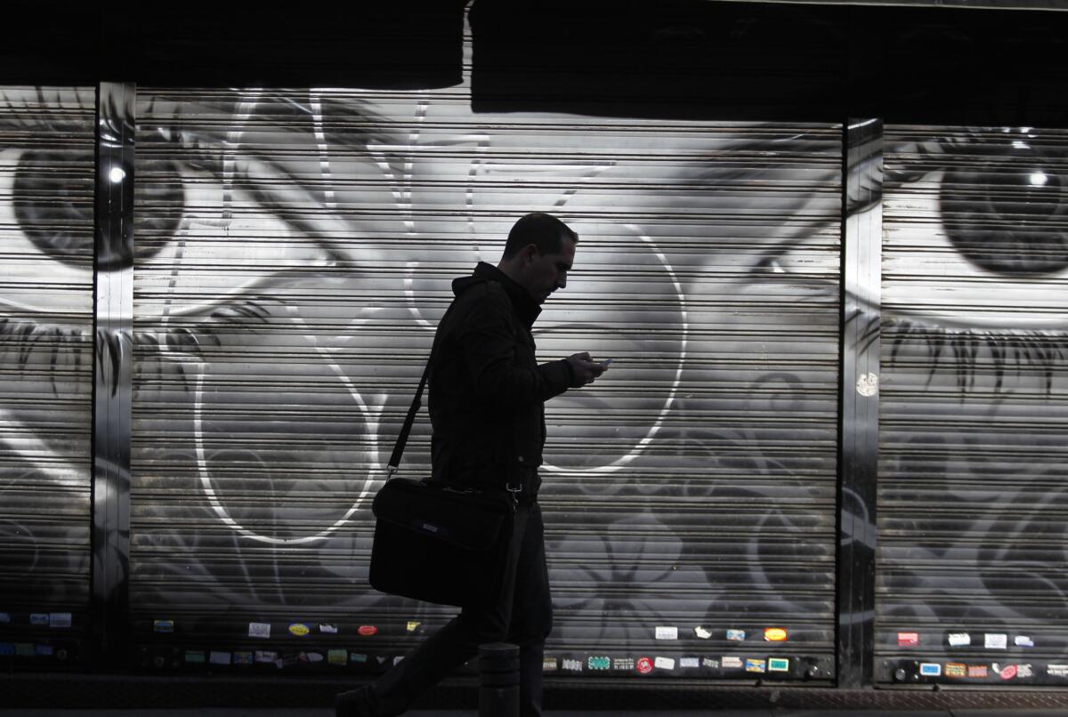 A man looks at his cellphone as he walks on the street in downtown Madrid. The National Security Agency tracks the locations of nearly 5 billion cellphones every day overseas, including those belonging to Americans abroad, the Washington Post reported Wednesday.