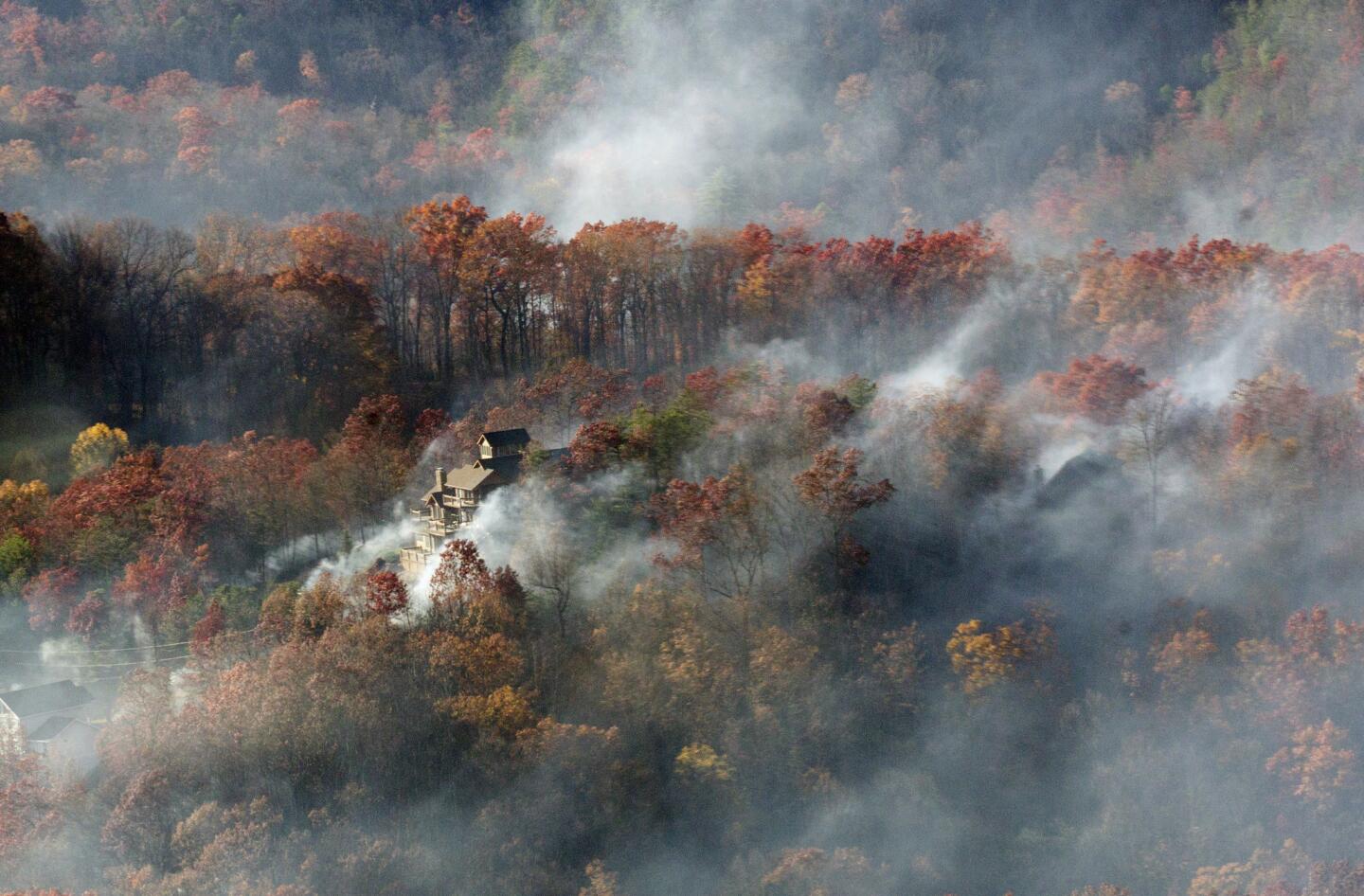 Smoke surrounds a home as seen from aboard a National Guard helicopter near Gatlinburg, Tenn. Thousands of people have fled deadly wildfires that have destroyed hundreds of homes and a resort in the Great Smoky Mountains.