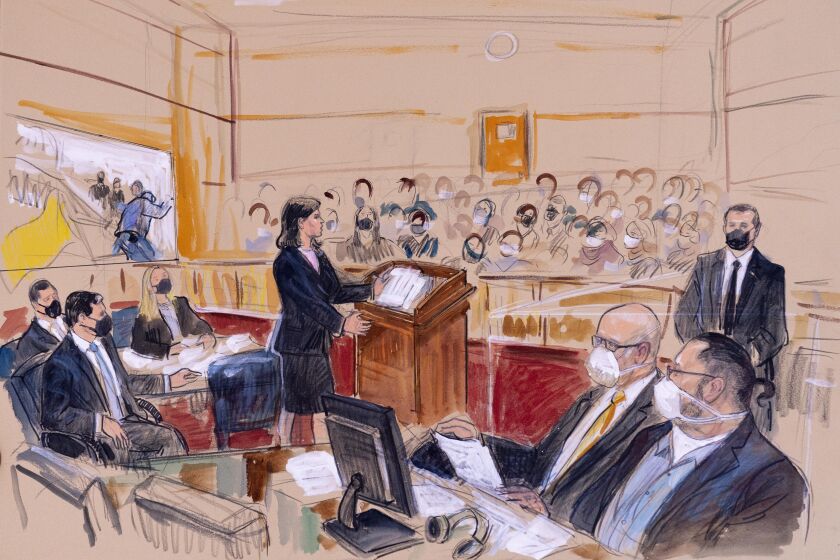 This artist sketch depicts Guy Wesley Reffitt, bottom right, joined by his lawyer William Welch, third from right, listening as prosecutor Risa Berkower, speaks at the podium at center, as a video depicts a handgun on the waist of Reffitt, at left, for members of the jury and audience in Federal Court, in Washington, Monday, March 7, 2022. Reffitt, a Texas man charged with storming the U.S. Capitol with a holstered handgun on his waist, is the first Jan. 6 defendant to go on trial. Also pictured from left, are prosecutors Tom Ryan, Jeff Nestler, and Amanda Rohde. Man at top right is unidentified, (Dana Verkouteren via AP)