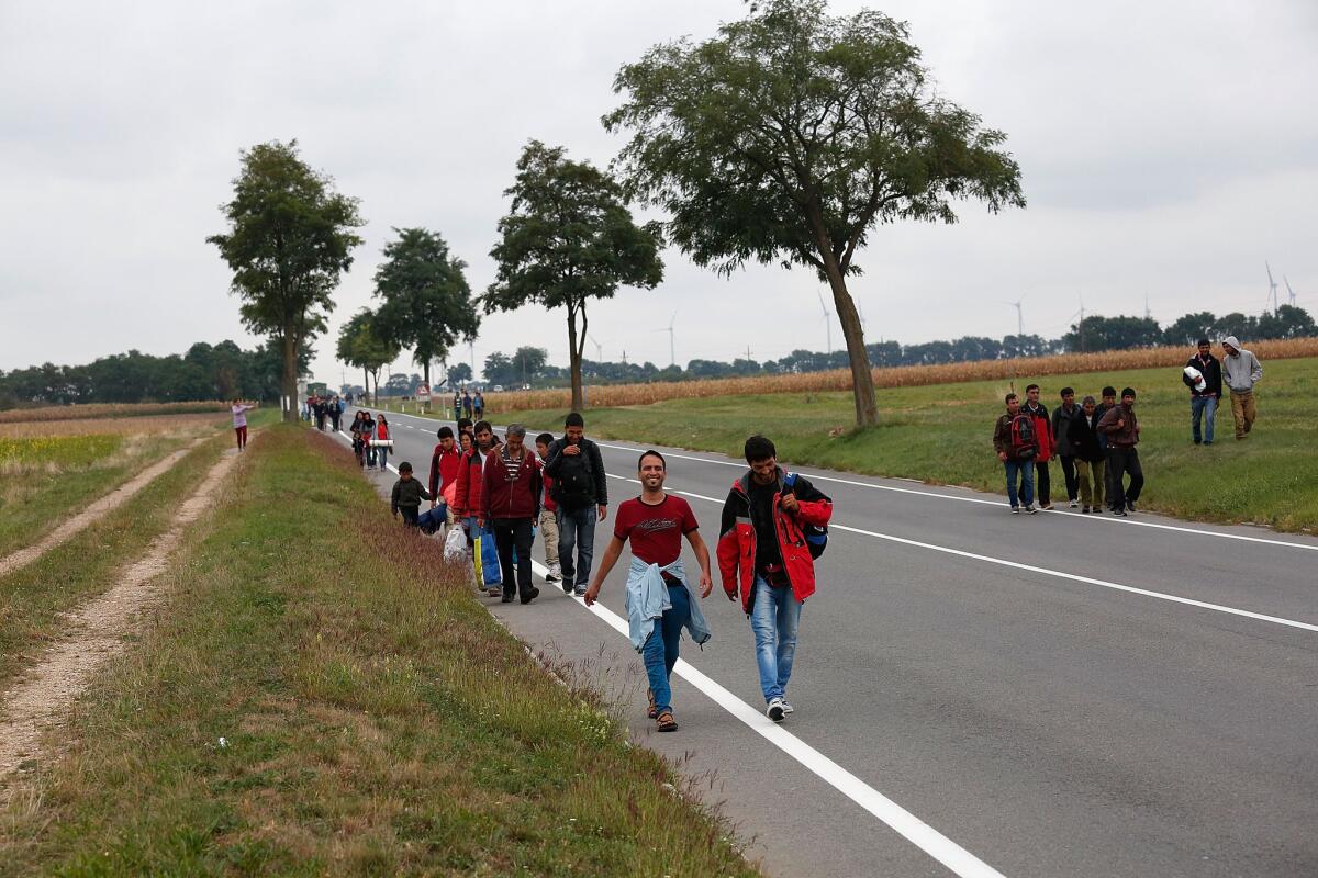 Refugees and migrants set off on foot along a road near Nickelsdorf, Austria, after authorities suspended train service due to an overload of the system at the border with Hungary on Sept. 11.