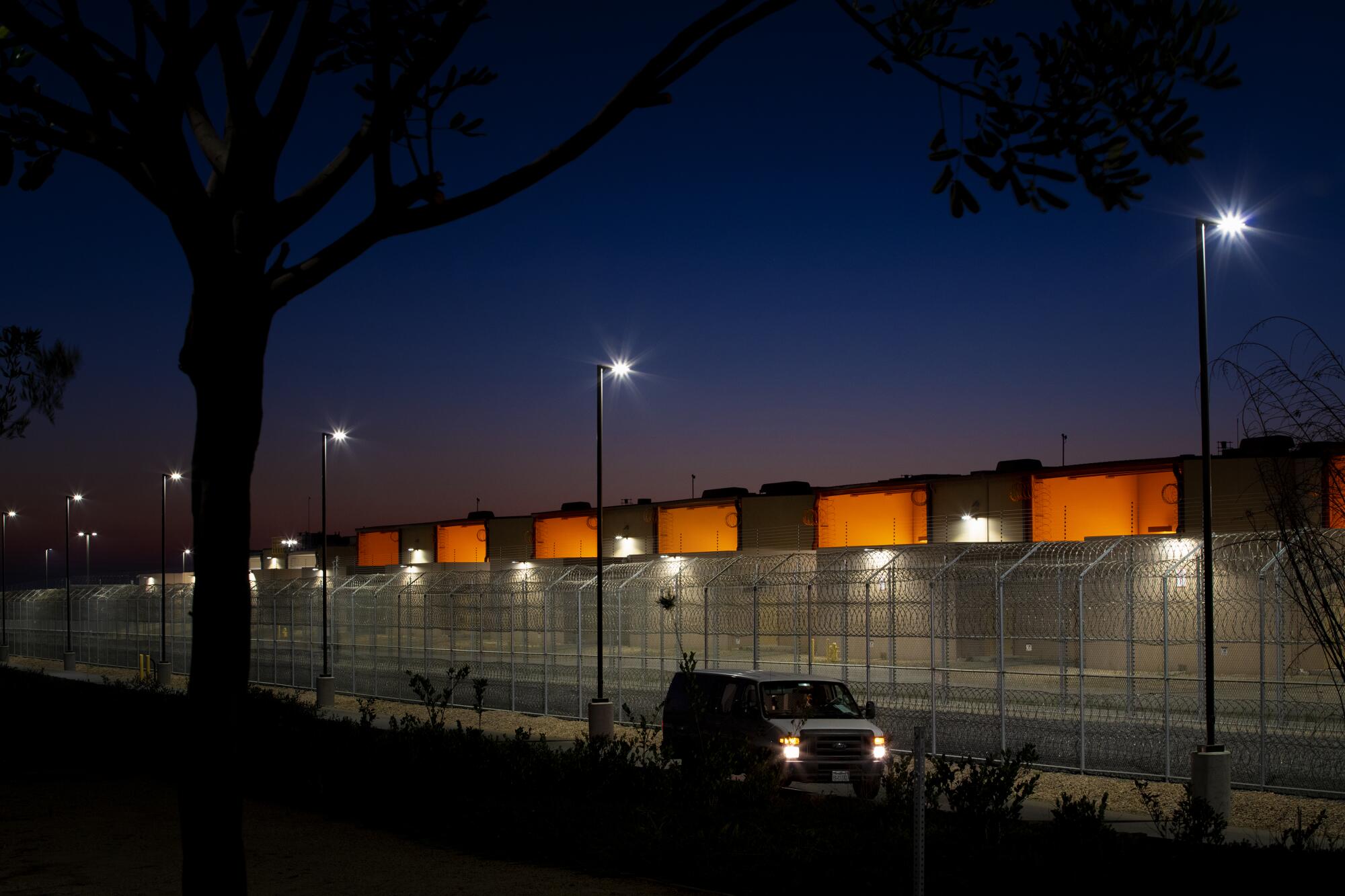 Otay Mesa Detention Center's fencing and the side of the building are brightly lit at night