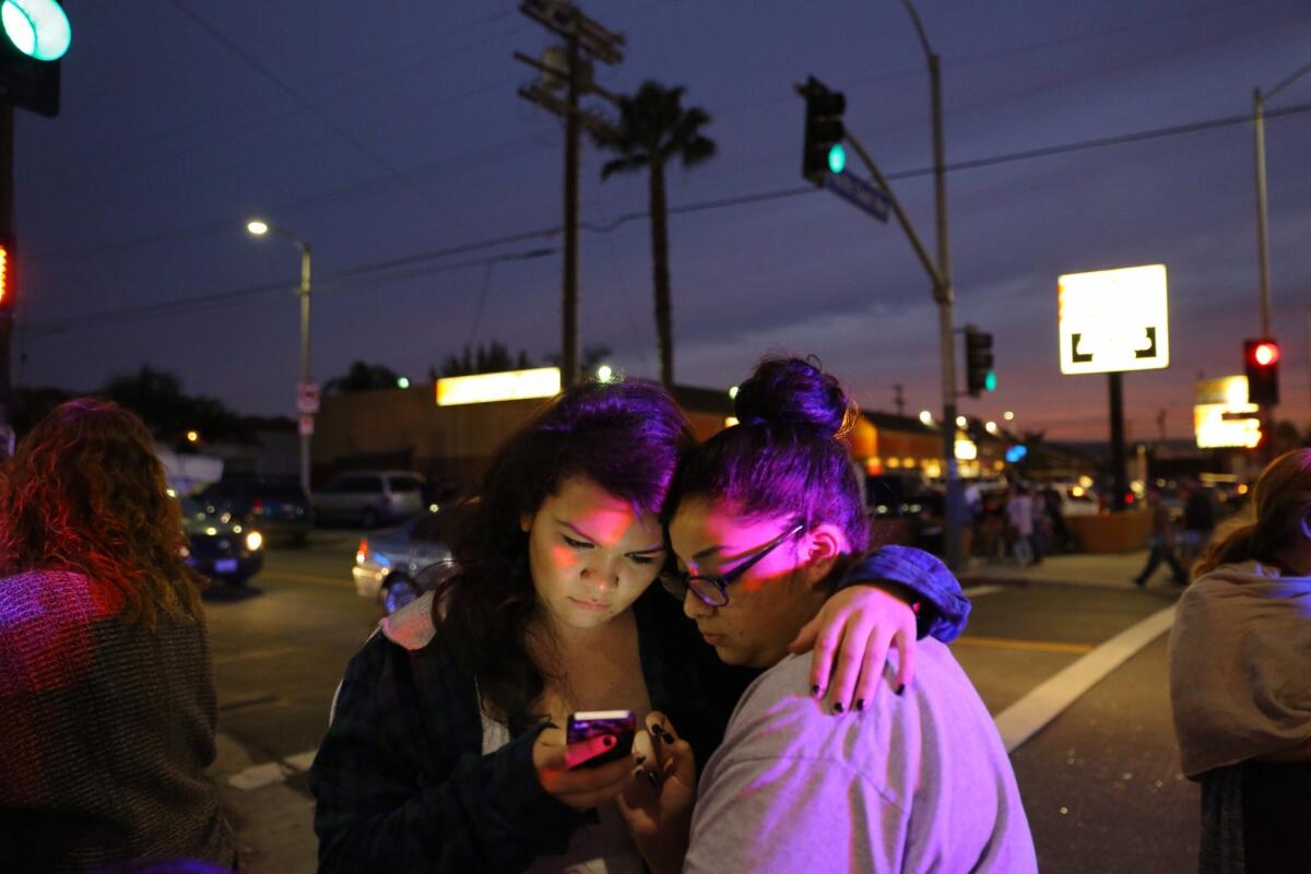 Ariel Ysais, left and Rebekah Garcia, check for news updates at the scene of the crash Thursday on Pacific Coast Highway in Wilmington.